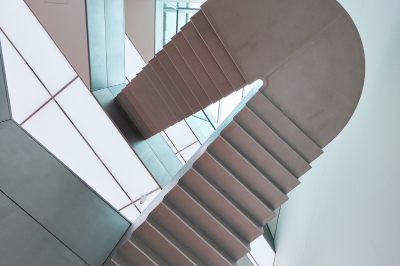 The picture shows a floating staircase inside the Heidi Horten Collection in Vienna.
It connects two floors of the museum.

The walls and ceilings are white and modern in design.
There are large windows through which daylight enters.
Everything looks bright, calm and clear.