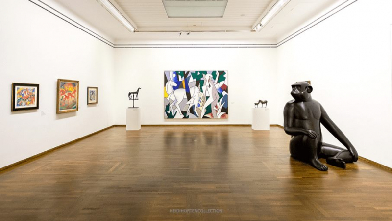 Moderne Kunstwerke und Skulpturen in einer hellen Galerie mit Holzfußboden.