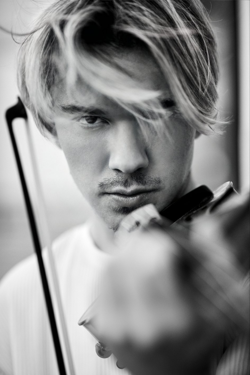 Junger Mann mit blonden Haaren spielt Geige, intensiver Blick, schwarz-wei&szlig; Fotografie.